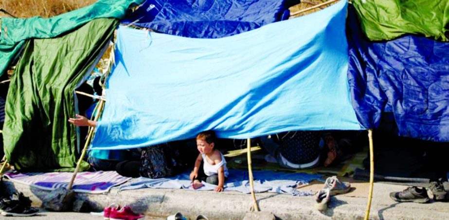 A baby sits in a tent as refugees and migrants from the destroyed Moria camp are sheltered near a new temporary camp, on the island of Lesbos, Greece on Tuesday.