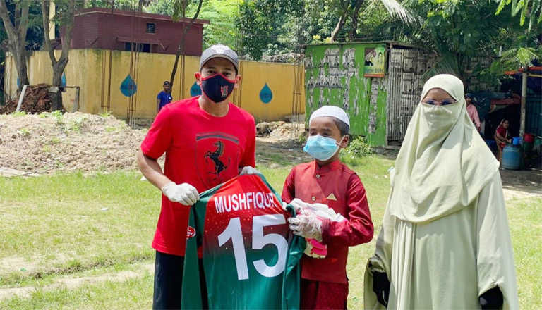 Mushfiqur Rahim (left) handing over his jersey to Sheikh Yaamin Sinan (centre) at Banani field in the city on Wednesday. Yaamin's mother is also seen in the picture.