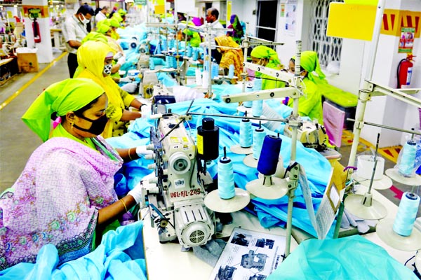 Workers are seen producing disposable medical gowns at a factory in Dhaka.