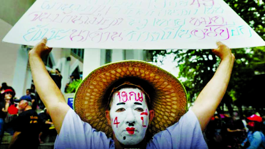 A pro-democracy protester with a painted face holds a placard as he attends a mass rally to call for the ouster of prime minister Prayuth Chan-ocha's government and reforms in the monarchy, in Bangkok, Thailand on Saturday.