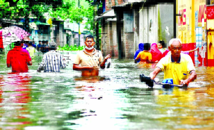 People wade through a road in Rangpur city submerged under waist-deep water following record rainfall in the district on Sunday.