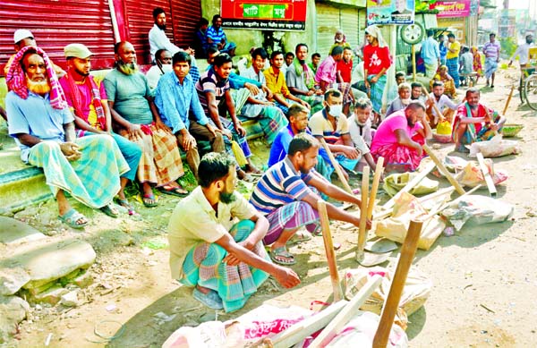 Many day-labourers, who depend on daily incomes, sit idle beside a road at Shanir Akhra in the capital on Friday as the economic downturn caused by the ongoing Covid-19 pandemic reduced work opportunities worsening their livelihood.