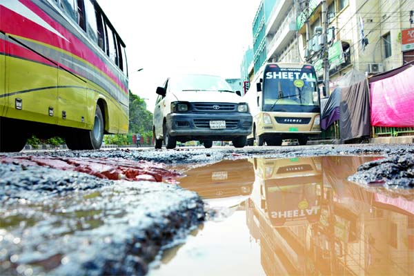 Vehicles struggle to move through a dilapidated road in the capital's Paltan area on Friday as big potholes developed there due to construction work.