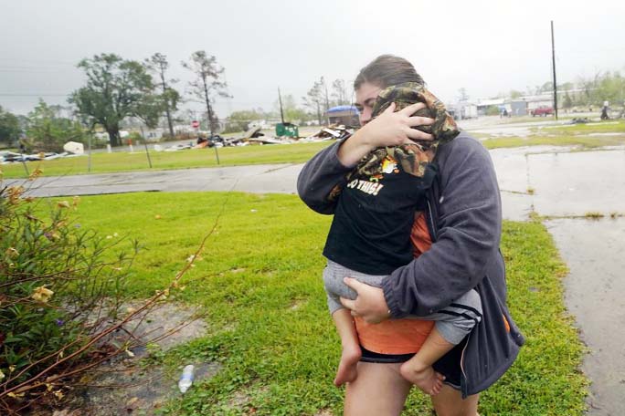 Danielle Fontenot runs to a relative's home in the rain with her son Hunter as Hurricane Delta approached Lake Charles, Louisiana on Friday.