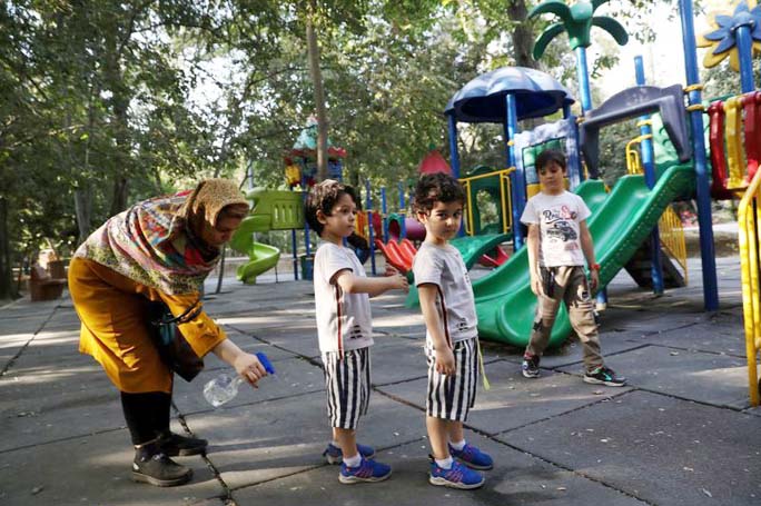 An Iranian woman disinfects her children at the park, amid the outbreak of the coronavirus, in Tehran.