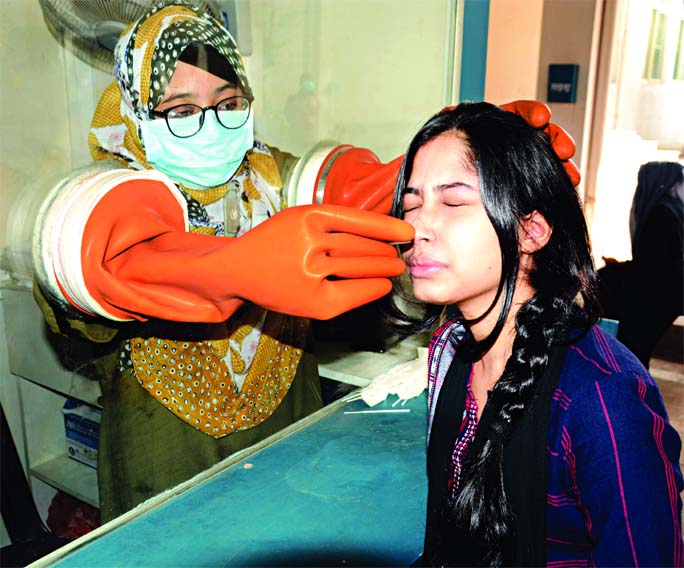 A female medical technologist with face mask collects nasal swab sample of a young girl to get tested Covid-19 at a booth in the capital's Mughda General Hospital on Saturday, amid falling death toll from the deadly virus in the country.