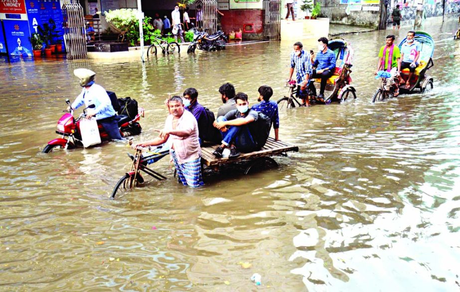 Van and rickshaws carrying passengers pass through a water-logged street in the capital's Green Road area after a brief rain on Wednesday.