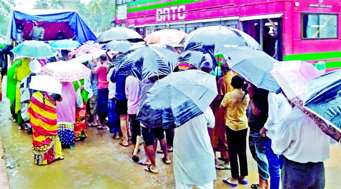 People wait in queues to buy potatoes from a TCB truck near Bangladesh Secretariat Bhaban in Dhaka on Thursday despite heavy rain in the capital.