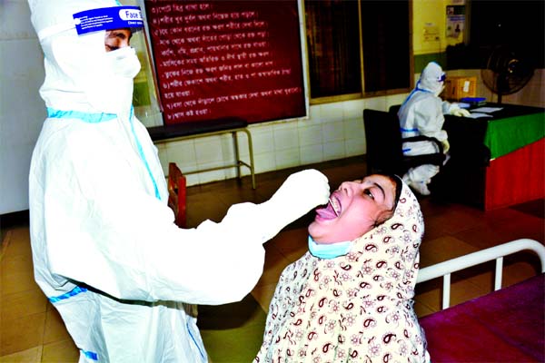 A lab technician collects swab from a girl to get tested coronavirus at Mugda General Hospital in the capital on Tuesday.