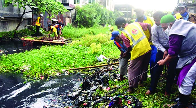 CCC administrator Khorshed Alam sujan joins hands with the conservancy workers of the corporation while cleaning the accumulated garbage of Ishaqer Pool in Bakalia in the port city on Wednesday .