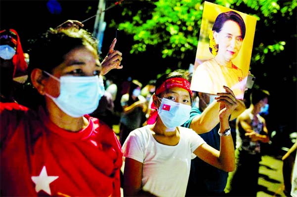 A supporter of National League for Democracy holds a picture of Myanmar State Counsellor Aung San Suu Kyi as she waits for results outside the party headquarters after the general election in Yangon, Myanmar.