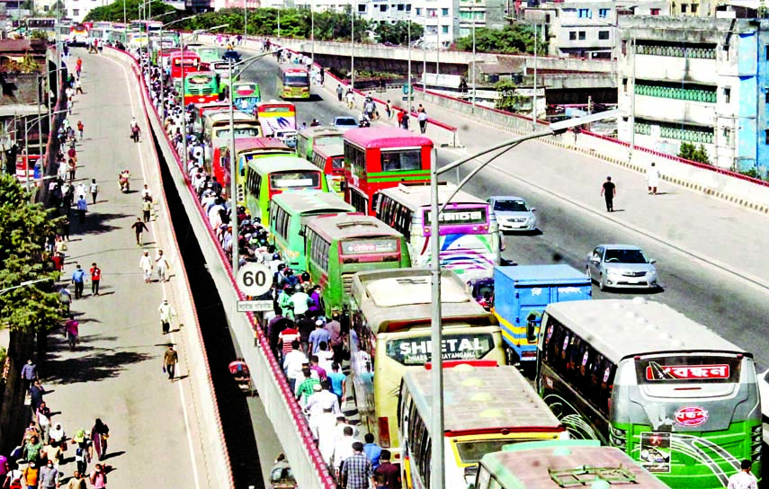 Passengers get off from public buses and take to Mayor Hanif Flyover at Jatrabari in the capital on Tuesday after large number of vehicles got stuck in traffic jam on the flyover.