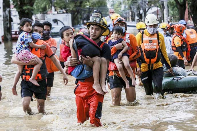 Rescuers carry children out from a flooded street due to heavy rains brought by Typhoon Vamco in Providence village in Marikina City, east of Manila, Philippines, Thursday.