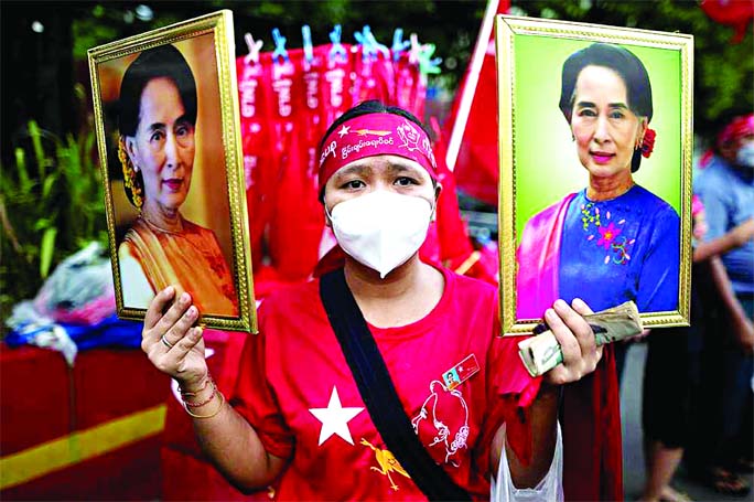 A National League for Democracy (NLD) supporter holds two portraits of Myanmar State Counsellor Aung San Suu Kyi as people gather to celebrate at party headquarters in Yangon, Myanmar.