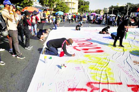 People write on poster during a rally to call for the ouster of Prime Minister Prayut Chan-o-cha's government and reforms in the monarchy in Bangkok, Thailand on Saturday.