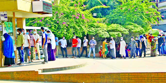 People stand in a long queue in front of the main entrance of Mugda General Hospital to get tested for coronavirus. The photo was taken on Saturday.