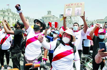 A person holds a sign with photos of two demonstrators killed during protests as people celebrate the resignation of interim President Manuel Merino in Lima, Peru.