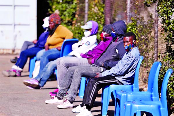 Some of the first South African Covid-19 vaccine trialists wait outside a clinic in Soweto.