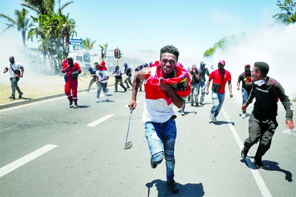 People run away from tear gas during protest against alleged racism outside Brackenfell High School in Cape Town.