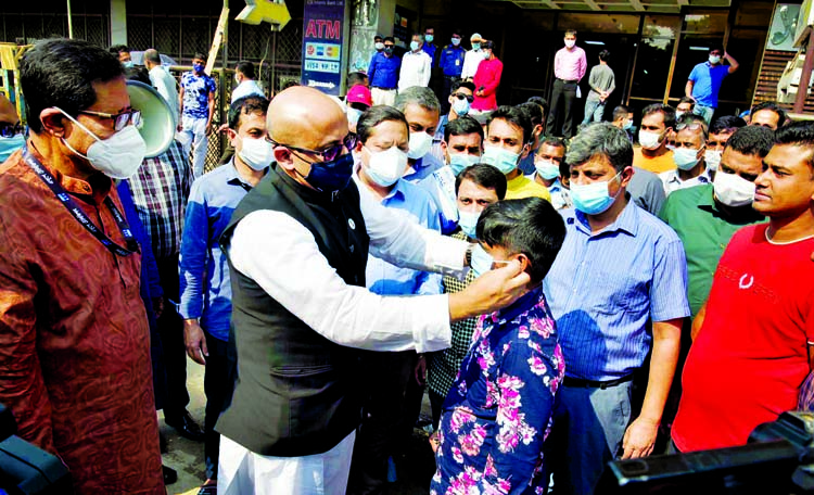 State Minister for Information Dr. Md Murad Hasan distributes masks among people in order to prevent Coronavirus adjacent to Saarc Fowara (Fountain) at Karwan Bazar in the capital on Sunday.