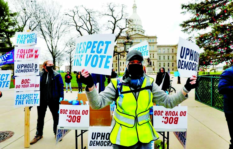 Supporters of US President-Elect Joe Biden stand in front of the Michigan State Capital as the Michigan Board of State Canvassers vote today to certify the 2020 election, in Lansing, Michigan.