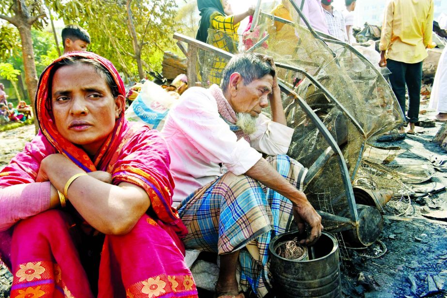 People are seen sitting in distressed condition as their shanties gutted in fire. This photo was taken from Sattala Basti, Mohakhali in the capital on Tuesday.