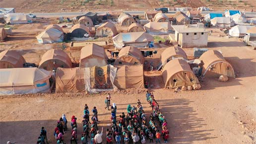 An aerial view of displaced Syrian youths standing in a queue ahead of classes before tents-transformed classrooms at a camp for the internally displaced in Maarrat Misrin town in Idlib Province.