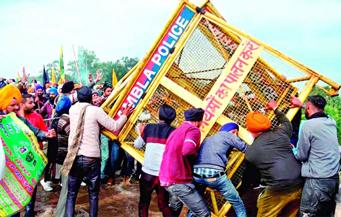 Farmers remove a police barrier blocking a road during a protest march to India's capital New Delhi against the central government recent agricultural reforms, on the outskirts of Ambala on Thursday.