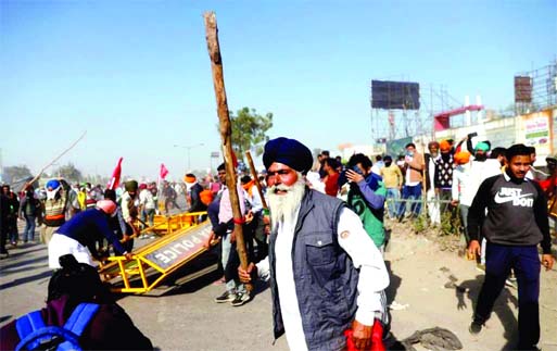 A farmer brandishes a stick during a protest against the newly passed farm bills at Singhu border near Delhi on Friday.