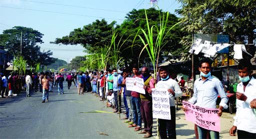 Workers and employees of Faridpur Sugar Mills form a human chain on Dhaka- Khulna Highway at Modhukhali Rail Gate in the district on Saturday demanding payment of their arrear salaries.