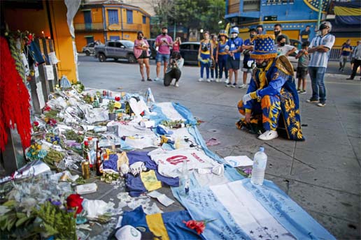 A fan mourns in front of flowers and posters left in tribute to Diego Maradona at the entrance of the Boca Juniors stadium known as La Bombonera in Buenos Aires, Argentina on Friday. The Argentine soccer great who was among the best players ever and who l