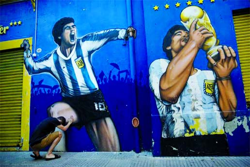 A man prays while touching a painting of Diego Maradona near the Boca Juniors stadium in Buenos Aires, Argentina on Friday.