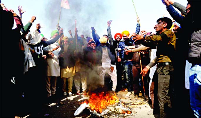 Farmers shout slogans as they burn an effigy during a protest against the newly passed farm bills at Singhu border near Delhi, India on Saturday.