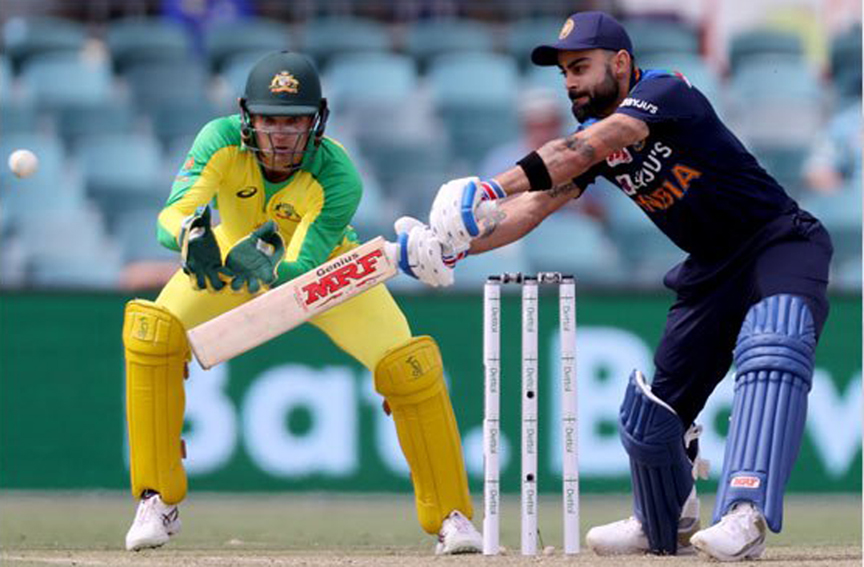 India captain Virat Kohli (right) plays a shot as Australia's wicketkeeper Alex Carey looks on during the third one-day international cricket match between Australia and India at Manuka Oval in Canberra on Wednesday.