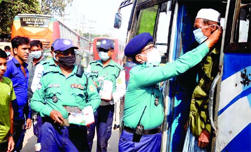 A CMP official gives a facemask to a bus passenger in Chattogram city on Wednesday as part of awareness campaign on Covid-19 pandemic.