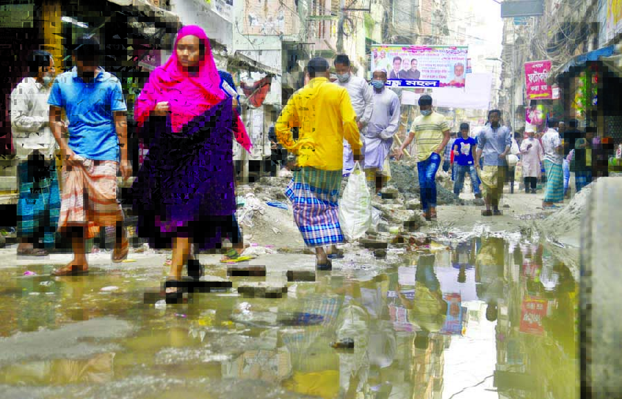 A woman crosses a waterlogged alley of Alubazar Road in old Dhaka on Thursday as it left dilapidated for months after digging due installation of sewerage pipelines.