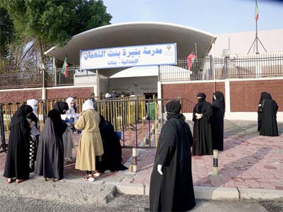 Kuwaiti women gather at the entrance of a polling station during parliamentary elections in Jahra City.