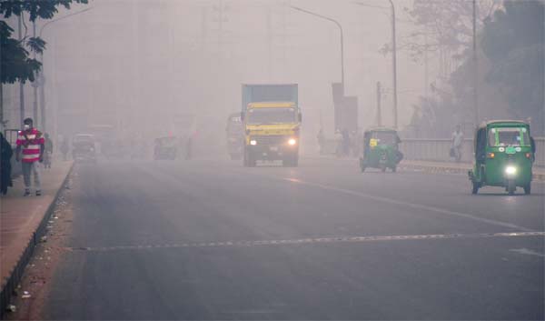 Vehicles ply on Buriganga Bridge turning their headlights on amid dense fog on Sunday morning.