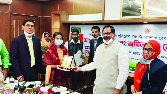Advocate Shamsul Alam Dudu, MP, hands over a crest to a Joyeeta at a ceremony at the DC conference room in Jaipurhat on Wednesday marking the Begum Rokeya Day.
