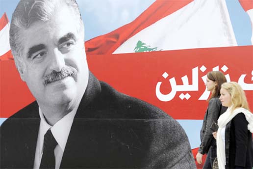 Two Lebanese women walking past a poster depicting late Lebanese prime minister Rafik Hariri, Beirut, Lebanon.