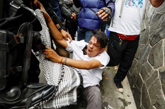 A man reacts while being detained by riot police officers during a protest over the detention of Rizieq Shihab, the leader of Indonesian Islamic Defenders Front (FPI), on suspicion of breaching coronavirus restrictions by staging several mass gatherings s