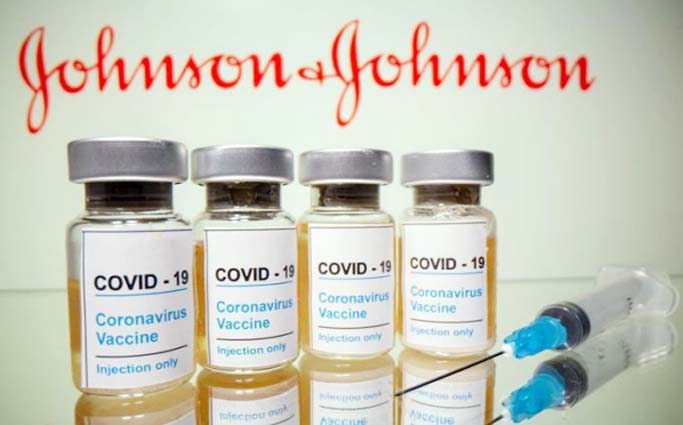 Vials and medical syringe are seen in front of J&J logo in this illustration.