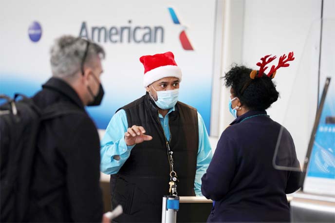 A passenger approaches two airline workers in Christmas-themed headwear at Ronald Reagan Washington National Airport, in Arlington, Virginia, US.