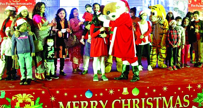 Santa Claus distributes chocolates along with masks among children like every year on the occasion of Christmas Day at Hotel Sonargaon in the capital on Friday.