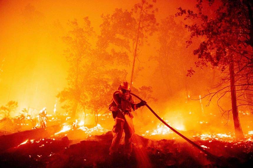 A firefighter douses flames as they push towards homes during the Creek fire in the Cascadel Woods area of Madera County, California.