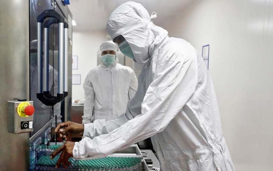 An employee in personal protective equipment (PPE) removes vials of AstraZeneca's COVISHIELD, coronavirus vaccine from a visual inspection machine inside a lab at Serum Institute of India, Pune, India.