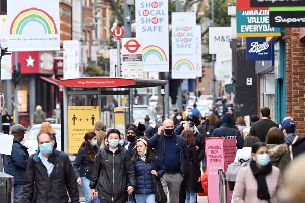 Pedestrians and shoppers, some wearing face masks as a precaution against the transmission of the novel coronavirus, walk in the high street, in London.