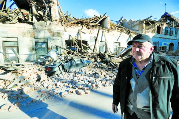 A man stands on a street next to destroyed houses on a street after an earthquake in Petrinja, Croatia on Tuesday.