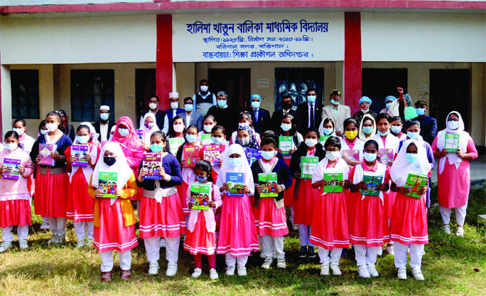 Barishal DC SM Ajiar Rahman and students pose for a photograph after distribution of secondary books at Halima Khatun Girls' Secondary School in the city on Friday.