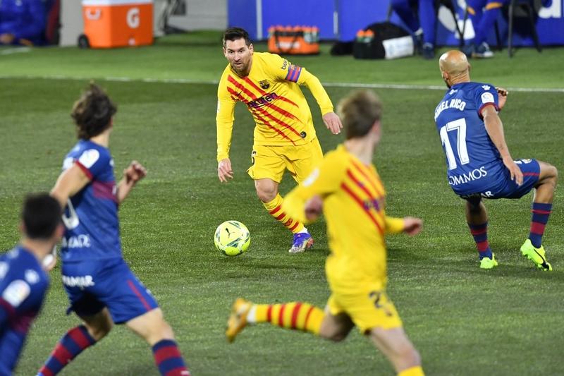 Barcelona's forward Lionel Messi (center) runs with the ball during the Spanish League football match against Huesca and Barcelona at the El Alcoraz stadium in Huesca on Sunday.